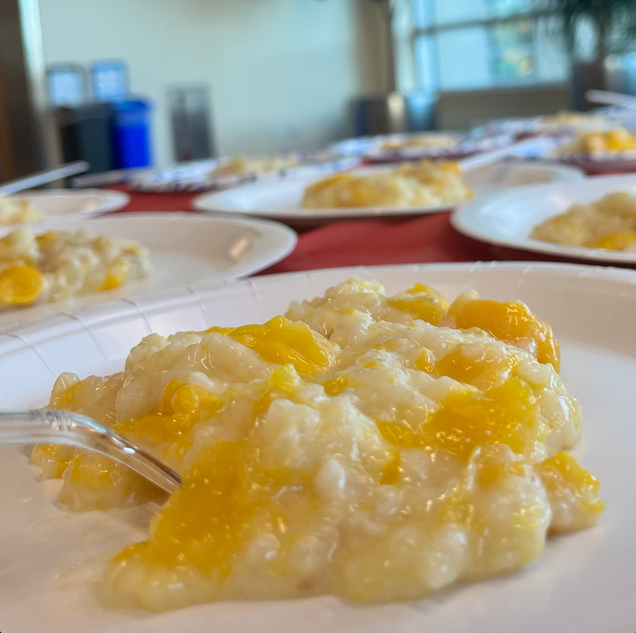 A cup of coconut mango rice pudding is plated with a fork push into the mixture on the left side.